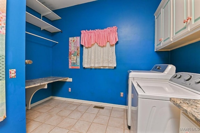 laundry room featuring cabinets, light tile patterned floors, and washer and clothes dryer