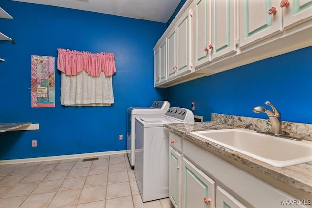 washroom featuring sink, light tile patterned floors, washing machine and dryer, and cabinets