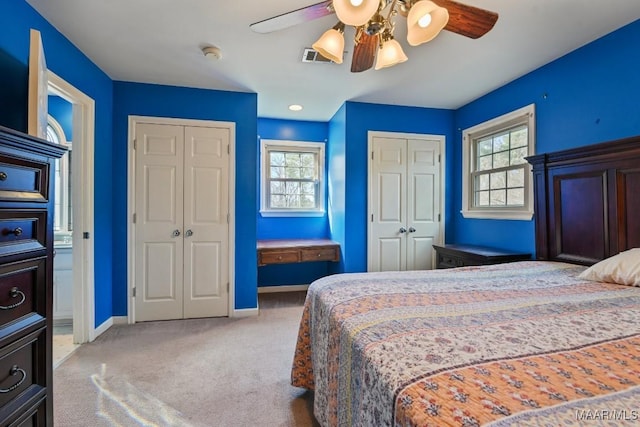 carpeted bedroom featuring ceiling fan and multiple closets