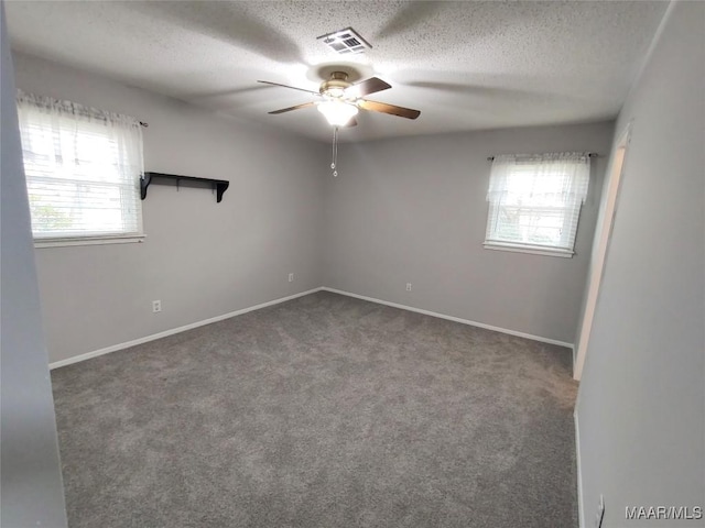 unfurnished room featuring ceiling fan, a textured ceiling, and dark colored carpet