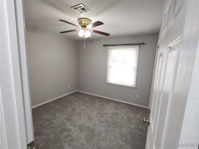 empty room with dark colored carpet, ceiling fan, and a textured ceiling