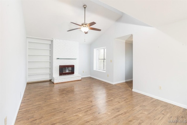 unfurnished living room featuring lofted ceiling, built in features, ceiling fan, wood-type flooring, and a brick fireplace