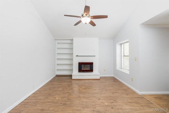 unfurnished living room with lofted ceiling, built in features, ceiling fan, a fireplace, and light wood-type flooring