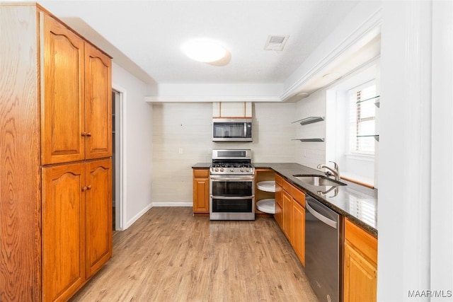 kitchen with sink, backsplash, light wood-type flooring, and appliances with stainless steel finishes