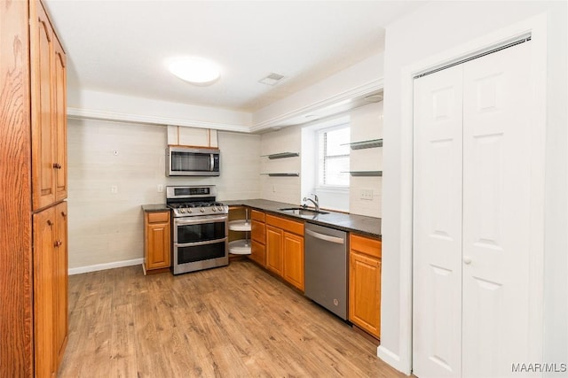 kitchen with sink, light wood-type flooring, and appliances with stainless steel finishes