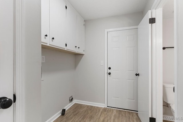 laundry room with light hardwood / wood-style floors and cabinets