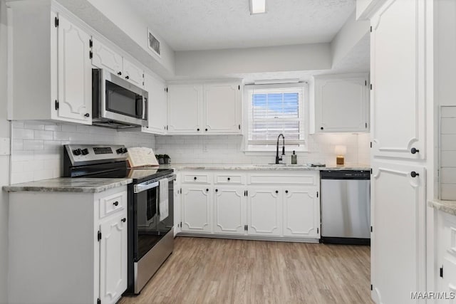 kitchen featuring sink, light hardwood / wood-style floors, white cabinets, and appliances with stainless steel finishes