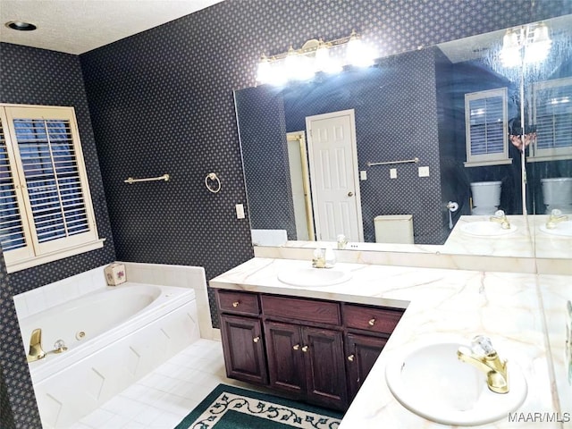 bathroom featuring a tub, vanity, toilet, tile patterned floors, and a textured ceiling