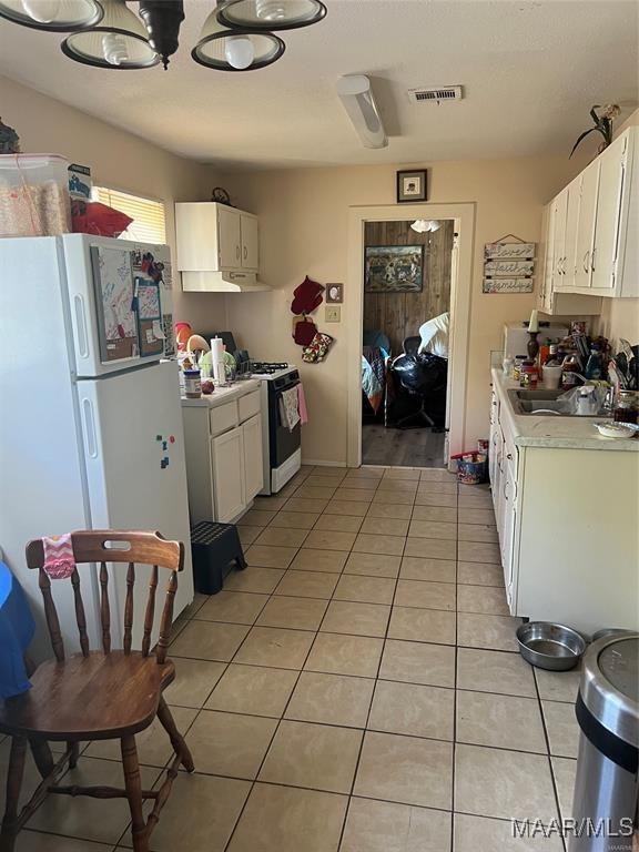 kitchen featuring light tile patterned floors, white appliances, sink, and white cabinets