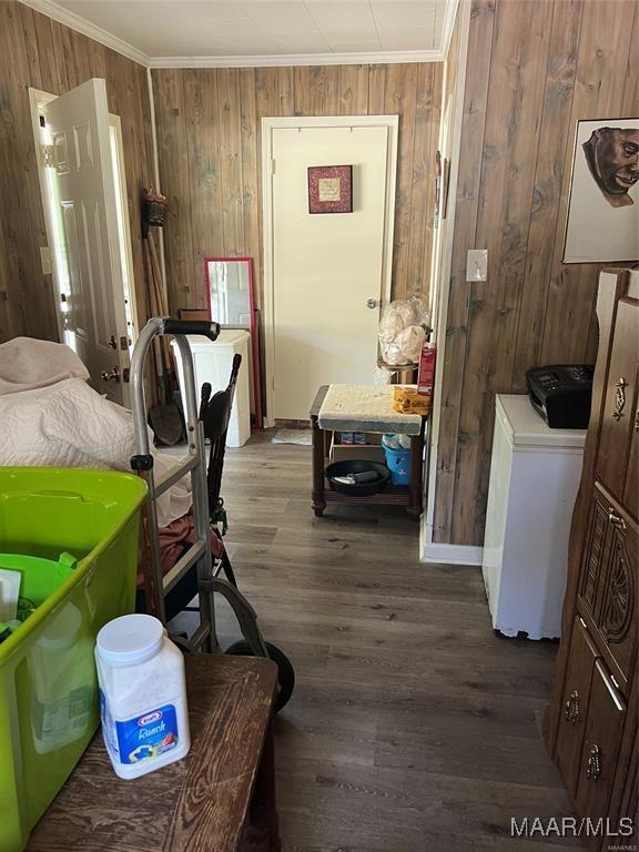 interior space with crown molding, wood walls, washer and dryer, and hardwood / wood-style flooring