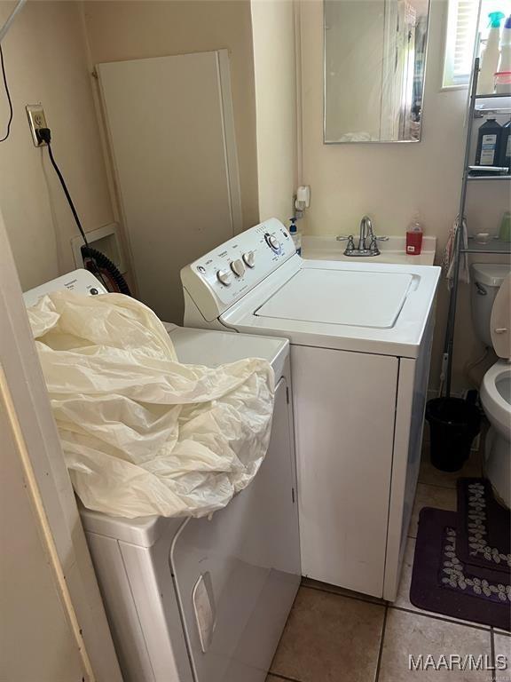 clothes washing area with light tile patterned floors and washer and clothes dryer