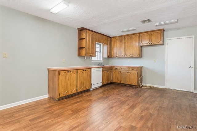 kitchen with white dishwasher, hardwood / wood-style floors, sink, and a textured ceiling