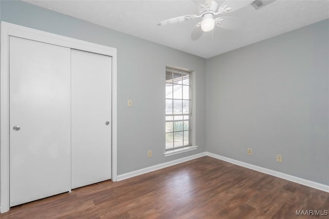 unfurnished bedroom featuring ceiling fan, dark hardwood / wood-style flooring, and a closet