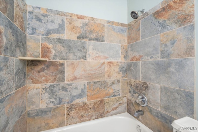 interior details with tiled shower / bath combo and toilet