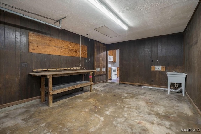 basement with wooden walls, sink, and a textured ceiling