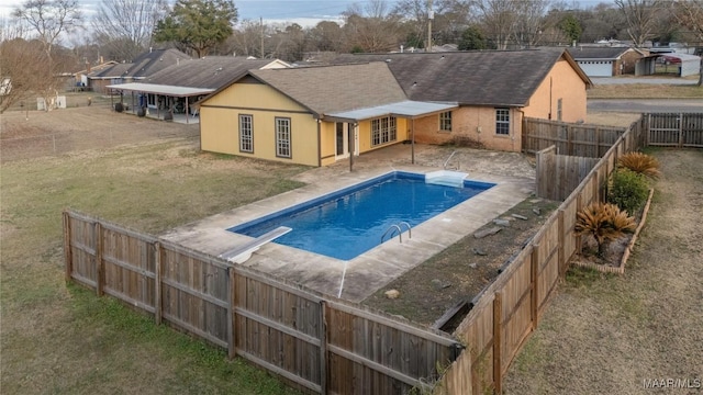 view of swimming pool with a yard and a diving board