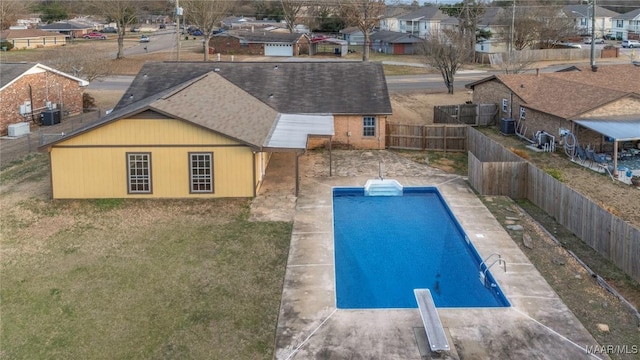 view of pool with central AC, a diving board, and a patio