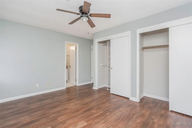 unfurnished bedroom with dark hardwood / wood-style floors, two closets, and ceiling fan