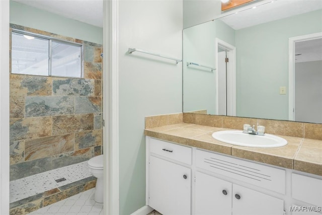 bathroom with vanity, toilet, and a tile shower