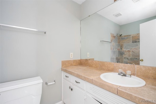 bathroom with vanity, toilet, and a shower