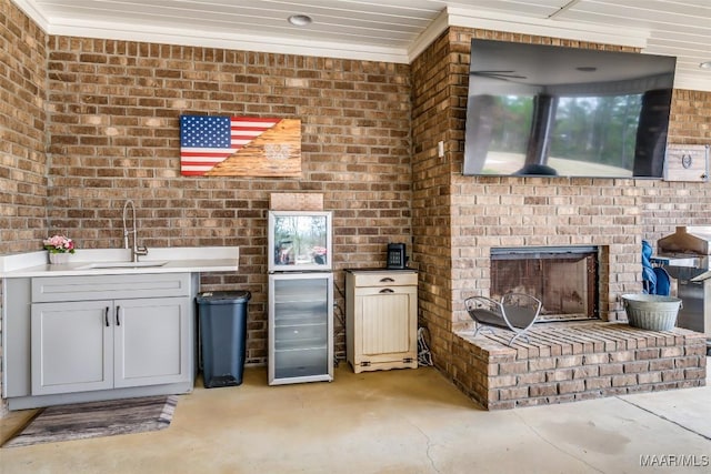 view of patio with a brick fireplace, beverage cooler, sink, and exterior kitchen