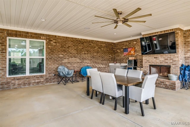 view of patio featuring an outdoor brick fireplace and ceiling fan