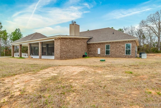 rear view of property with central AC unit, a yard, and a sunroom