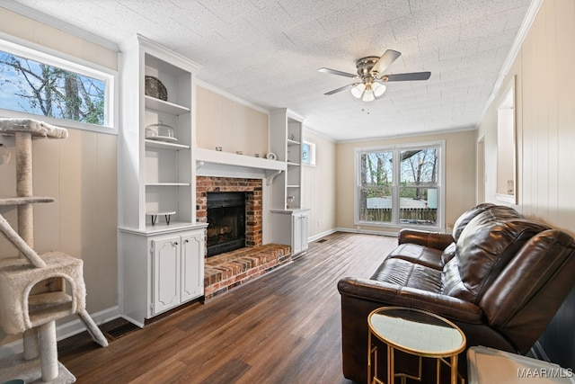 living room featuring crown molding, ceiling fan, dark hardwood / wood-style floors, a brick fireplace, and built in shelves