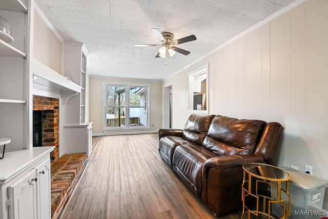 living room featuring dark hardwood / wood-style flooring, crown molding, a fireplace, and ceiling fan