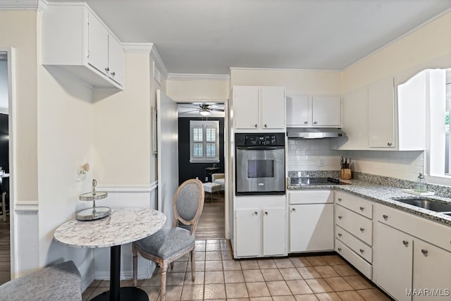 kitchen featuring black electric stovetop, sink, stainless steel oven, and white cabinets