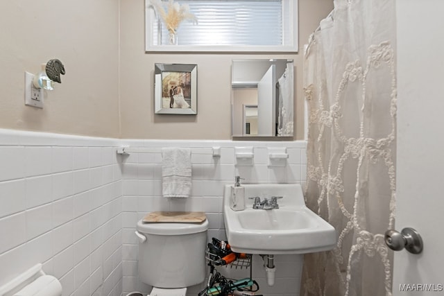 bathroom featuring toilet and tile walls