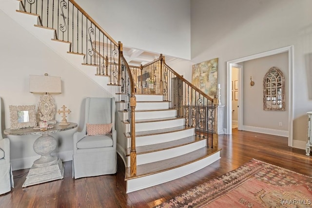 stairs featuring a high ceiling, coffered ceiling, hardwood / wood-style floors, and beam ceiling