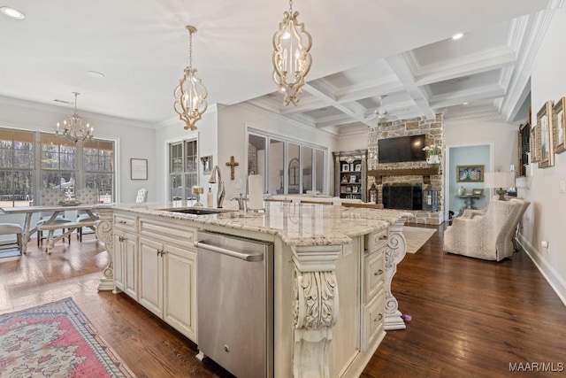 kitchen featuring a center island with sink, stainless steel dishwasher, light stone counters, and decorative light fixtures