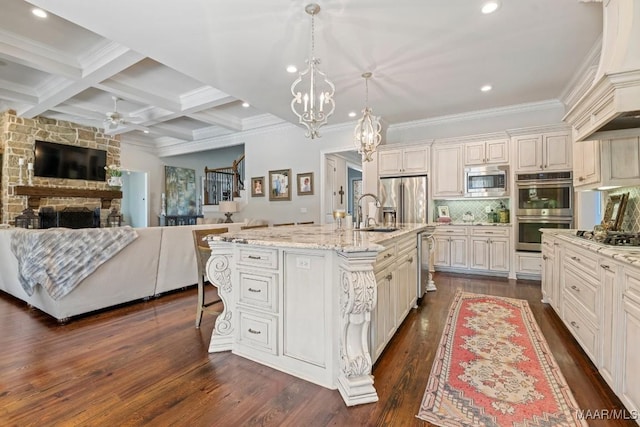 kitchen featuring pendant lighting, a breakfast bar, stainless steel appliances, light stone counters, and a center island with sink