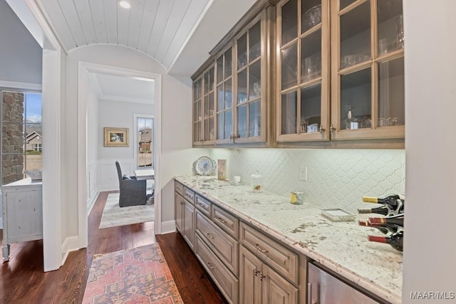 bar featuring vaulted ceiling, dark hardwood / wood-style flooring, decorative backsplash, ornamental molding, and light stone countertops