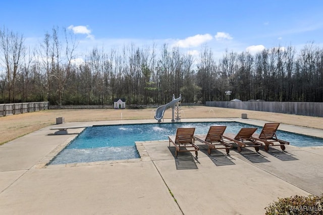 view of swimming pool with a water slide, a diving board, and a patio area