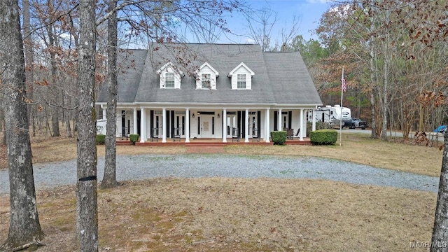 cape cod house with covered porch and a front yard