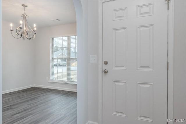 entrance foyer featuring plenty of natural light, dark hardwood / wood-style floors, and an inviting chandelier