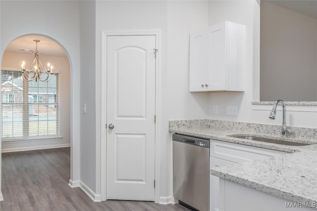 kitchen with sink, hardwood / wood-style floors, light stone countertops, white cabinets, and stainless steel dishwasher