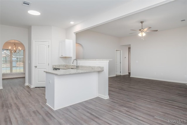 kitchen featuring dark hardwood / wood-style floors, ceiling fan with notable chandelier, sink, white cabinets, and light stone countertops