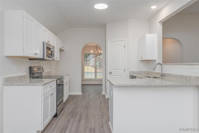 kitchen with sink, appliances with stainless steel finishes, light stone countertops, white cabinets, and kitchen peninsula