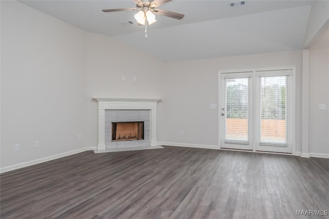 unfurnished living room with a tile fireplace, vaulted ceiling, dark wood-type flooring, and ceiling fan