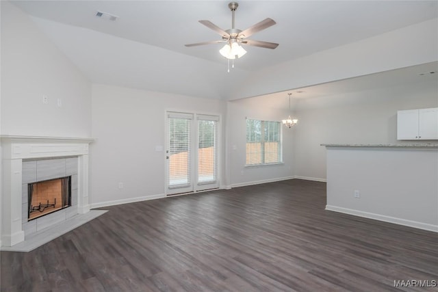 unfurnished living room featuring a tiled fireplace, ceiling fan with notable chandelier, dark wood-type flooring, and vaulted ceiling