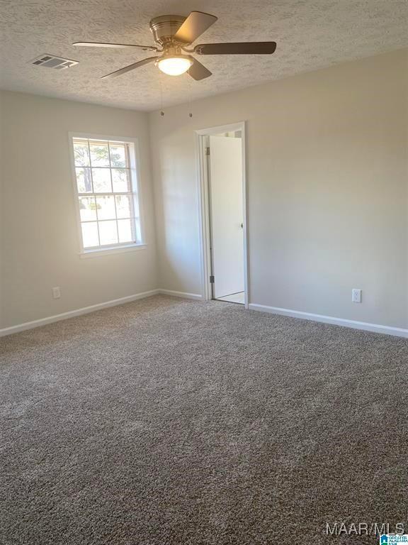 unfurnished room featuring ceiling fan, carpet flooring, and a textured ceiling