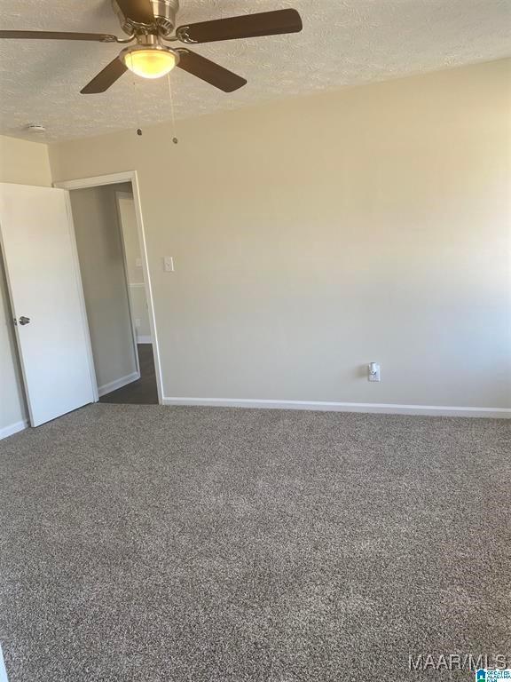 carpeted empty room featuring ceiling fan and a textured ceiling