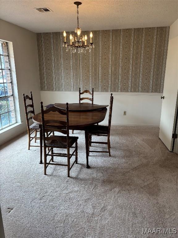 carpeted dining room with a textured ceiling and a notable chandelier