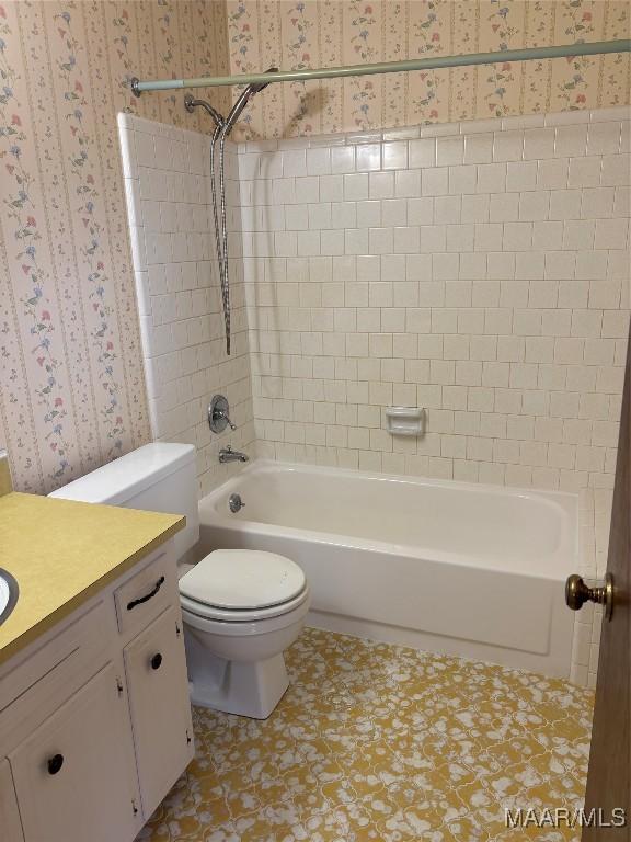 full bathroom with tiled shower / bath, vanity, and toilet