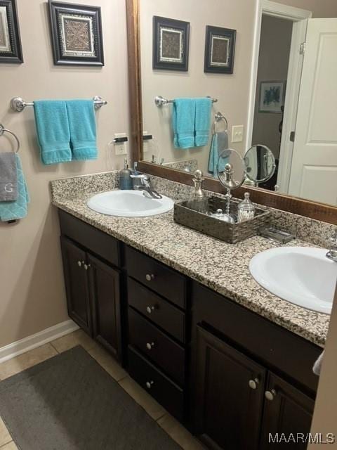 full bath with double vanity, tile patterned flooring, baseboards, and a sink