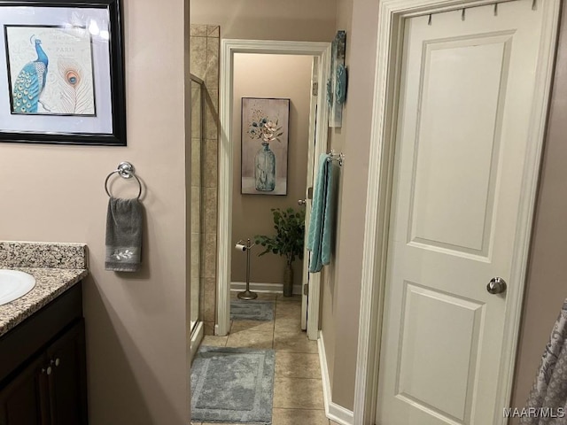 bathroom featuring a stall shower, vanity, baseboards, and tile patterned floors