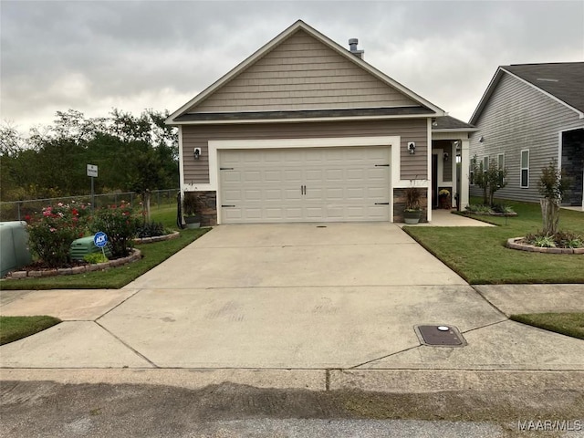 craftsman inspired home featuring concrete driveway, fence, a garage, stone siding, and a front lawn